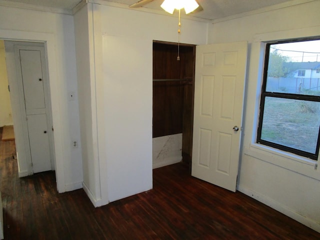 unfurnished bedroom featuring dark hardwood / wood-style flooring, a closet, ornamental molding, and ceiling fan