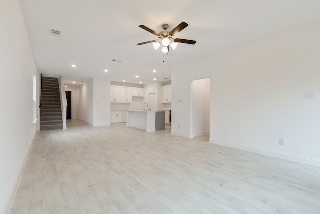 unfurnished living room with sink, light hardwood / wood-style floors, and ceiling fan