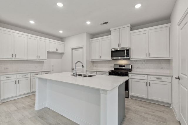 kitchen with sink, a center island with sink, white cabinets, and appliances with stainless steel finishes