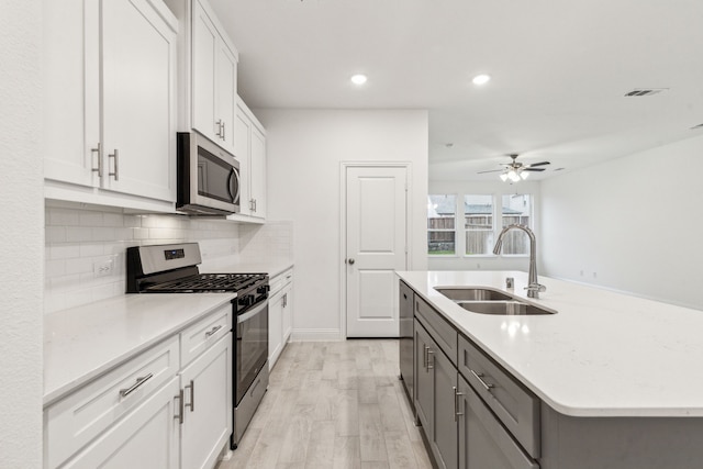 kitchen with tasteful backsplash, an island with sink, sink, white cabinets, and stainless steel appliances