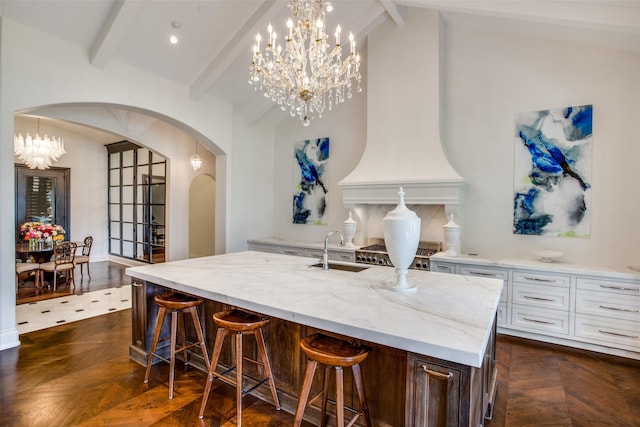 kitchen with dark parquet flooring, an island with sink, and white cabinets