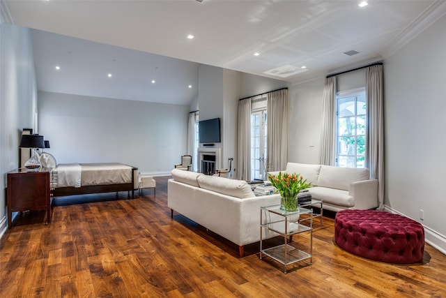 bedroom featuring lofted ceiling, a fireplace, crown molding, and wood-type flooring