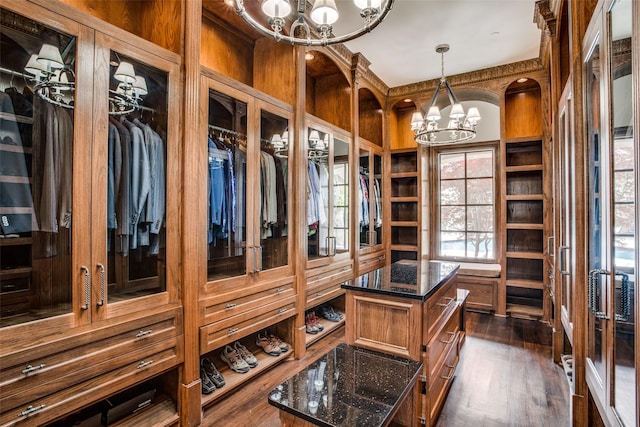 walk in closet featuring a notable chandelier and dark hardwood / wood-style flooring