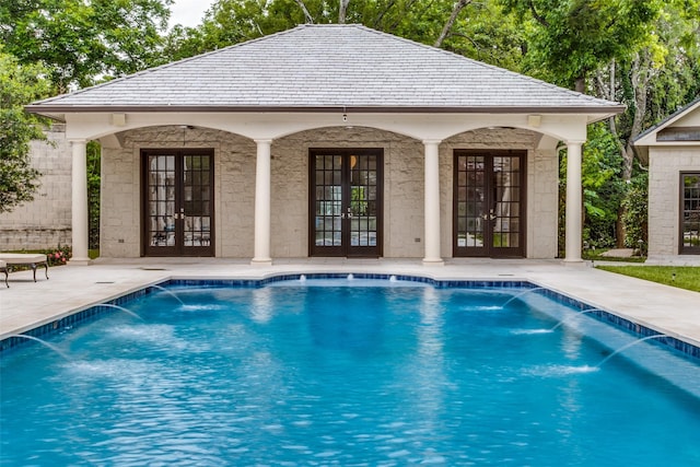 view of pool featuring french doors, pool water feature, and an outbuilding