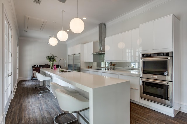 kitchen with white cabinets, an island with sink, and a kitchen bar