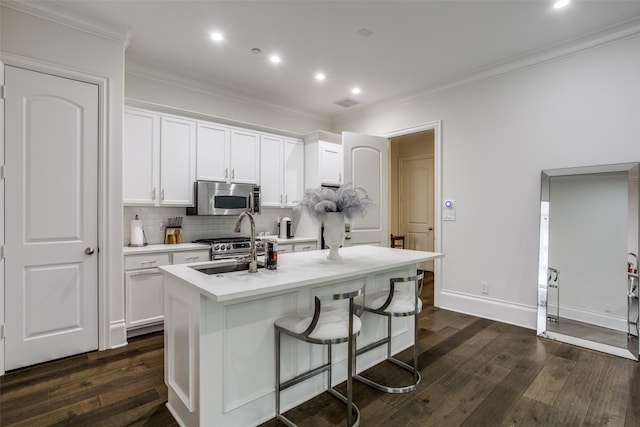 kitchen with an island with sink, dark wood-type flooring, appliances with stainless steel finishes, and white cabinets