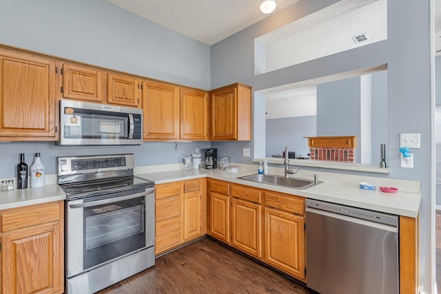 kitchen with a textured ceiling, appliances with stainless steel finishes, dark hardwood / wood-style floors, and sink