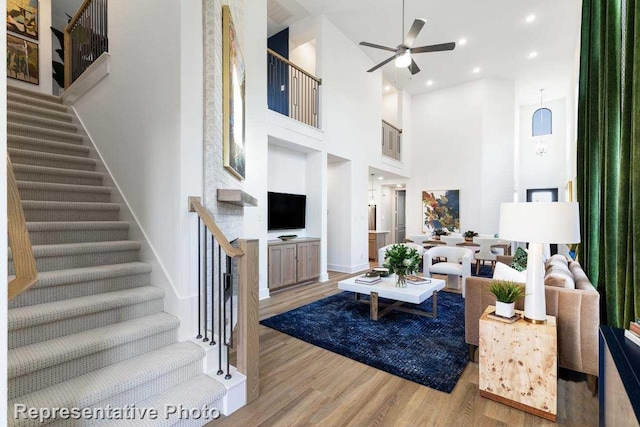 living room with a towering ceiling, light wood-type flooring, and ceiling fan