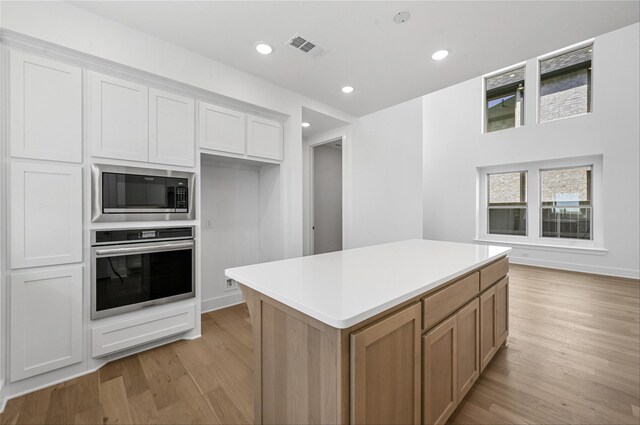 kitchen with light stone countertops, pendant lighting, stainless steel appliances, a kitchen island, and white cabinetry