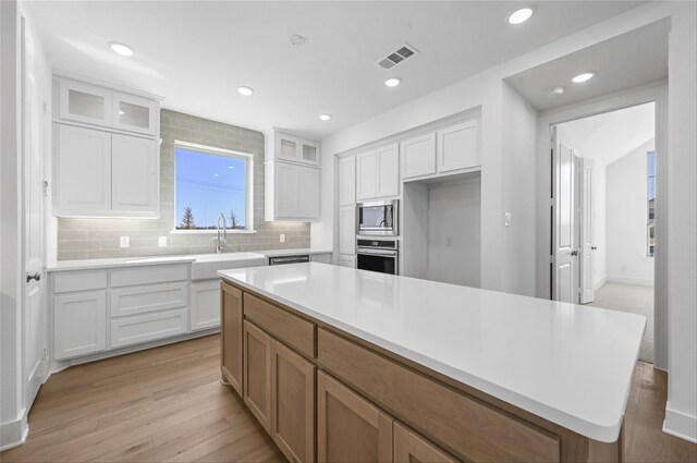 kitchen with stainless steel appliances, green cabinetry, white cabinets, a center island, and sink