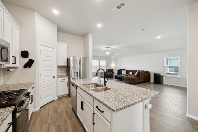 kitchen with a kitchen island with sink, sink, stainless steel appliances, and white cabinetry