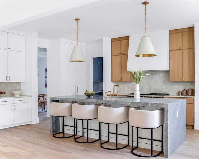 kitchen with decorative backsplash, white cabinetry, and hanging light fixtures