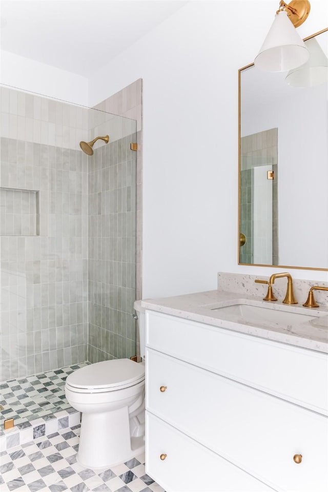 bathroom with tiled shower, vanity, and toilet