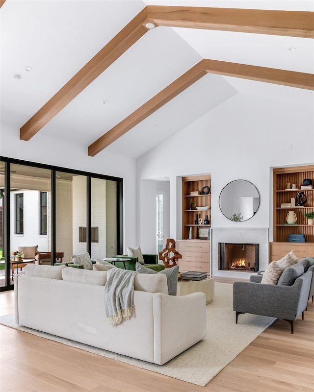 living room featuring a high end fireplace, high vaulted ceiling, built in features, and light hardwood / wood-style flooring