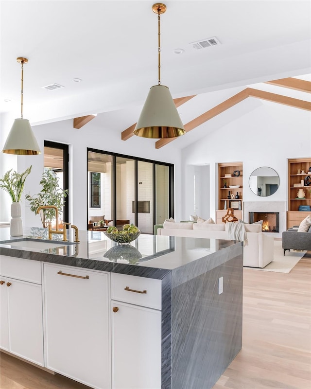 kitchen with sink, white cabinetry, pendant lighting, and built in features