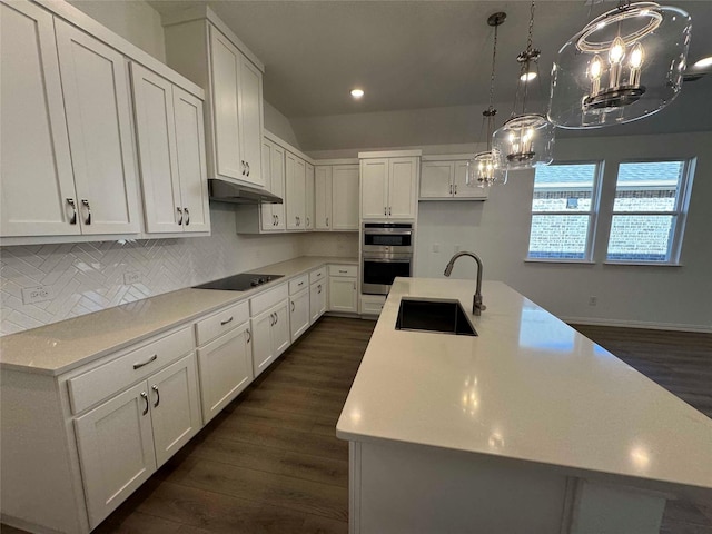 kitchen with a center island with sink, black electric stovetop, white cabinetry, and sink