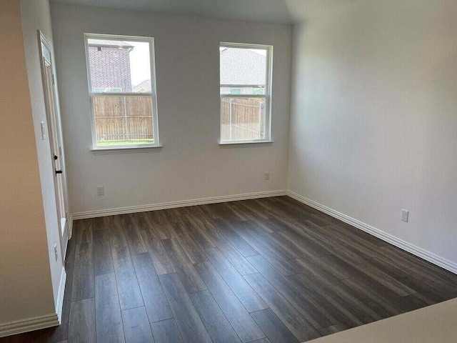 spare room with dark hardwood / wood-style flooring and a wealth of natural light