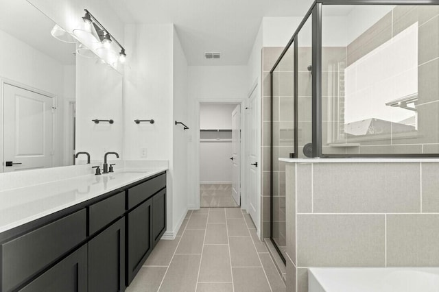 bathroom with tile patterned flooring, a shower with shower door, and vanity