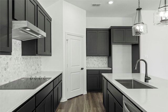 kitchen featuring hanging light fixtures, black electric stovetop, dark hardwood / wood-style floors, sink, and wall chimney range hood