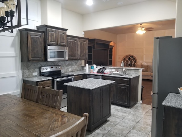 kitchen with stainless steel appliances, kitchen peninsula, a kitchen island, sink, and dark brown cabinets