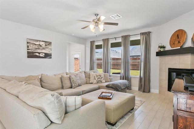 living room with ceiling fan, light hardwood / wood-style floors, and a tile fireplace