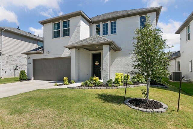 view of front of house with central AC unit, a front lawn, and a garage