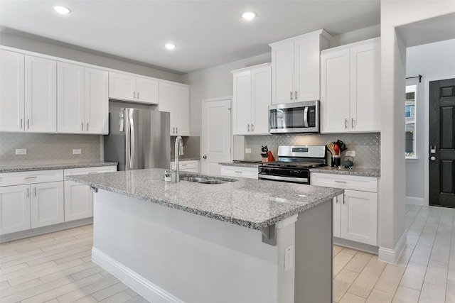 kitchen with white cabinetry, sink, stainless steel appliances, and a center island with sink