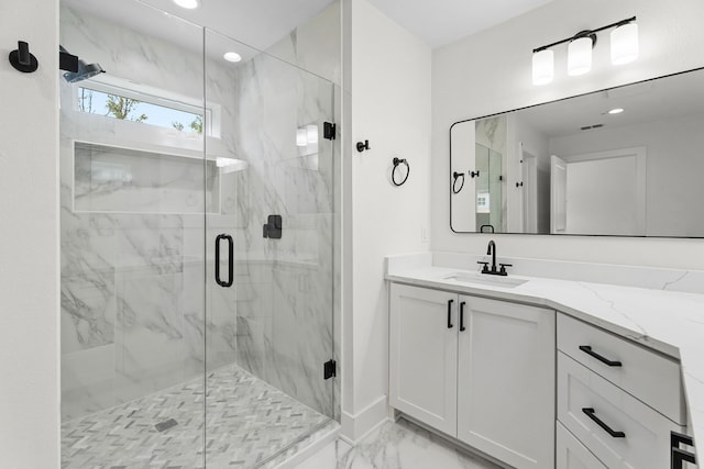 bathroom with a shower with shower door and vanity