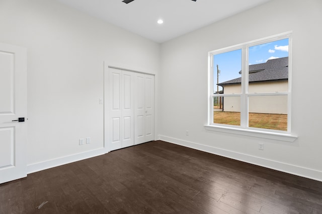 unfurnished bedroom with multiple windows, ceiling fan, a closet, and dark hardwood / wood-style floors