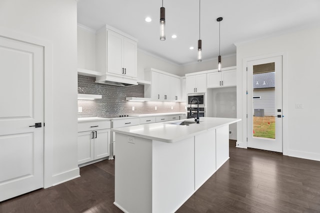 kitchen featuring pendant lighting, white cabinetry, a center island with sink, and stainless steel microwave