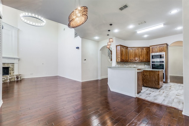 kitchen featuring hardwood / wood-style floors, stainless steel microwave, and hanging light fixtures