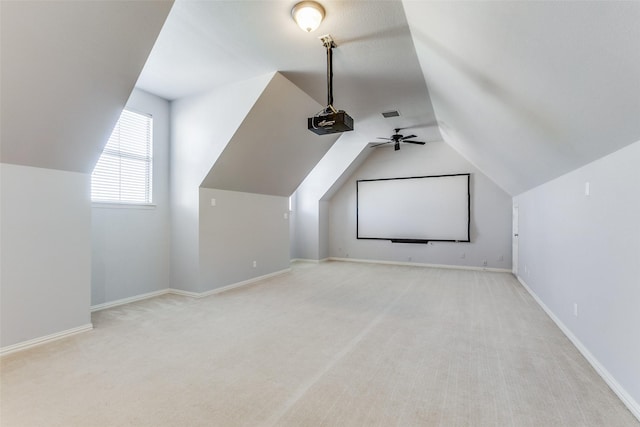 cinema room with light colored carpet, ceiling fan, and vaulted ceiling