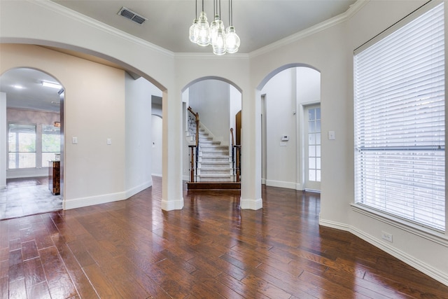 empty room with dark hardwood / wood-style flooring, ornamental molding, a healthy amount of sunlight, and a notable chandelier