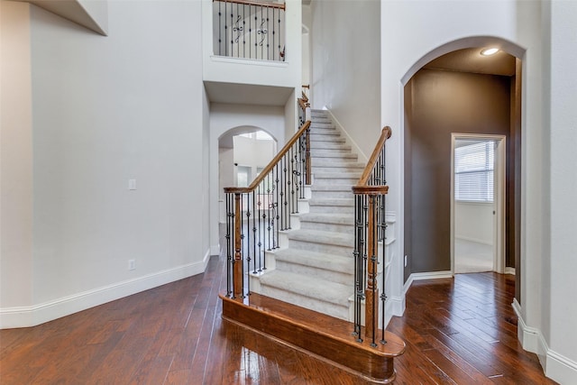 staircase featuring a high ceiling and wood-type flooring