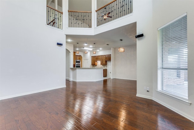 unfurnished living room featuring dark hardwood / wood-style flooring and a towering ceiling