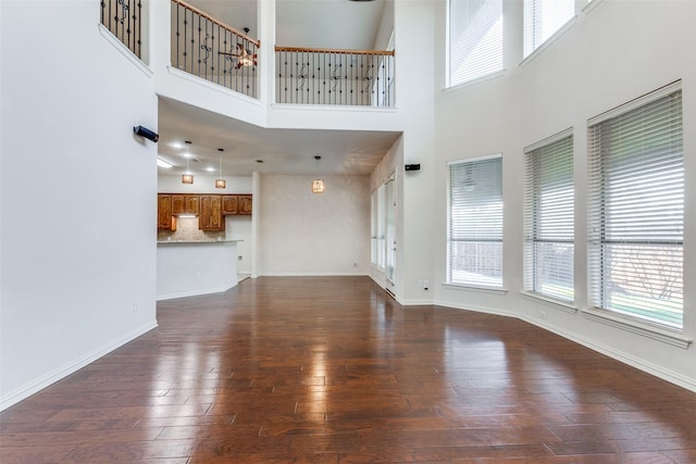 unfurnished living room with a towering ceiling and dark wood-type flooring