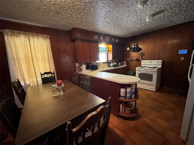 kitchen featuring white electric range, wood walls, kitchen peninsula, a textured ceiling, and sink