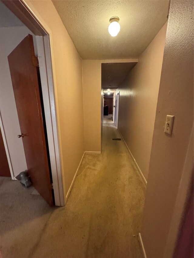 corridor with a textured ceiling and light carpet