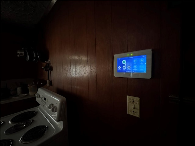 interior space featuring washer / dryer, wooden walls, and white range with electric stovetop