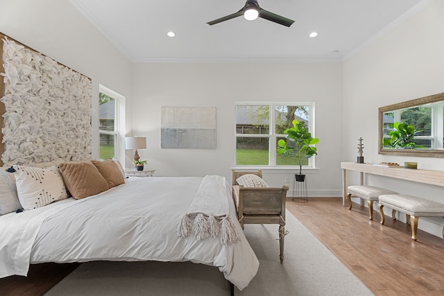 bedroom featuring ceiling fan, light hardwood / wood-style flooring, ornamental molding, and multiple windows