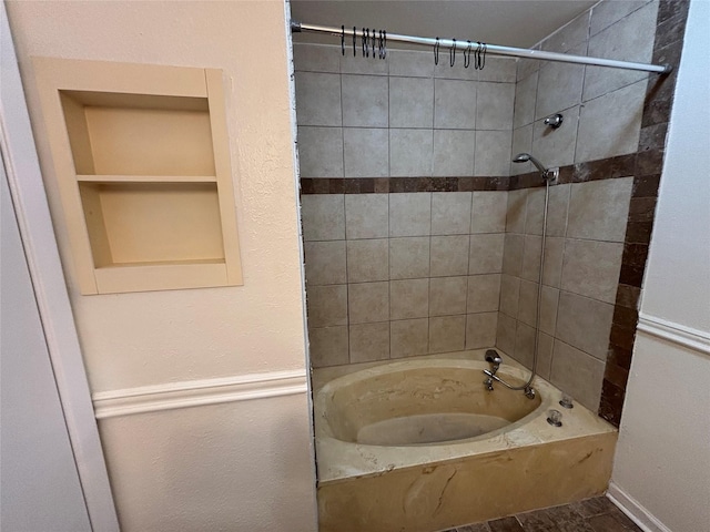 bathroom with tiled shower / bath combo and built in shelves