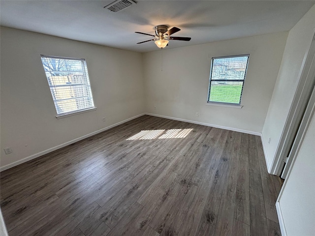 unfurnished room with ceiling fan, plenty of natural light, and dark wood-type flooring