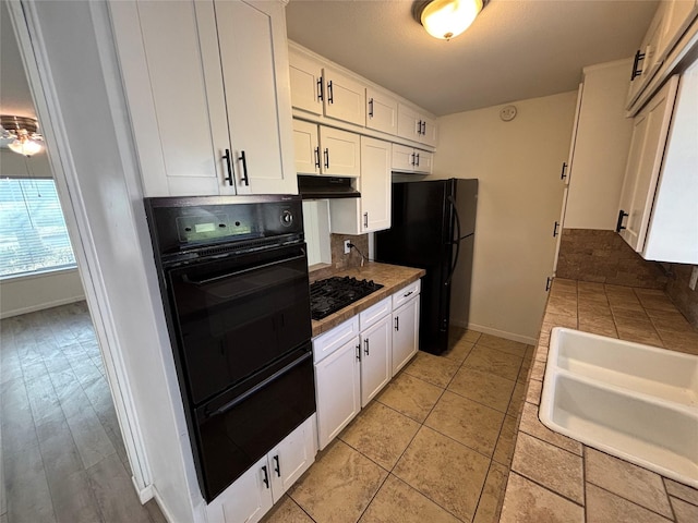 kitchen featuring black appliances, white cabinetry, sink, and light tile patterned floors