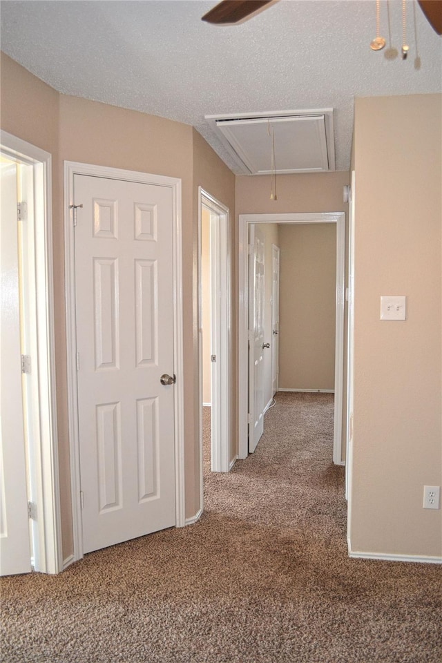 hall featuring a textured ceiling and carpet