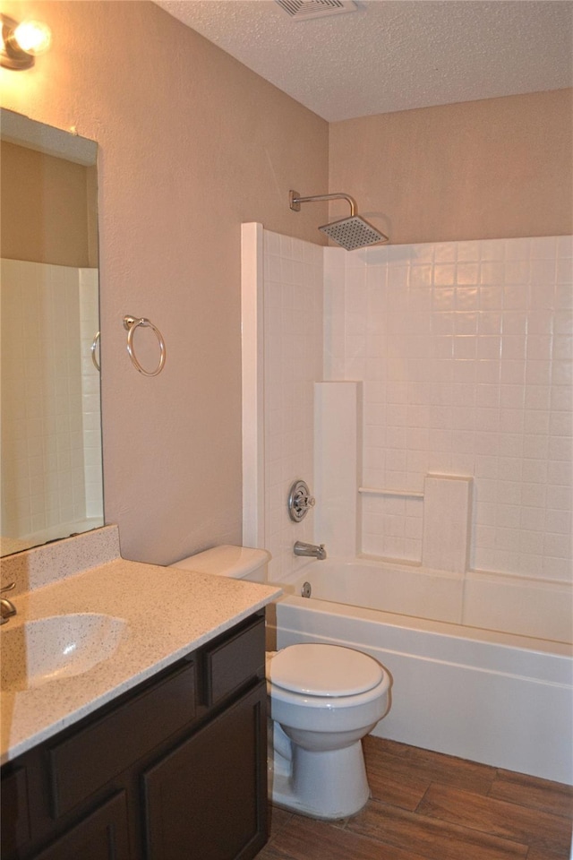 full bathroom with a textured ceiling, toilet, wood-type flooring, shower / bath combination, and vanity