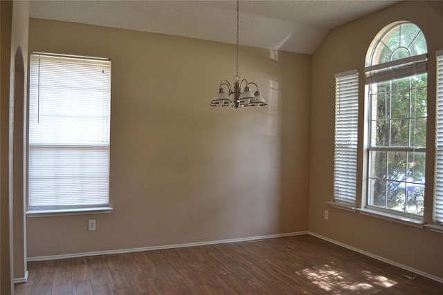 interior space with lofted ceiling, an inviting chandelier, a healthy amount of sunlight, and dark hardwood / wood-style floors