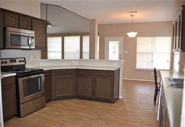 kitchen featuring stainless steel appliances, kitchen peninsula, ceiling fan, light hardwood / wood-style flooring, and decorative light fixtures