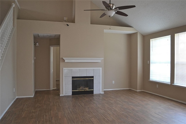 unfurnished living room featuring a textured ceiling, a wealth of natural light, a fireplace, ceiling fan, and wood-type flooring