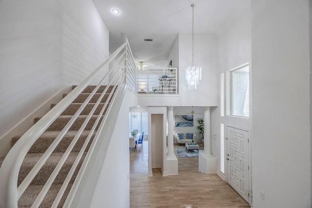 stairs with a high ceiling, a notable chandelier, and hardwood / wood-style floors