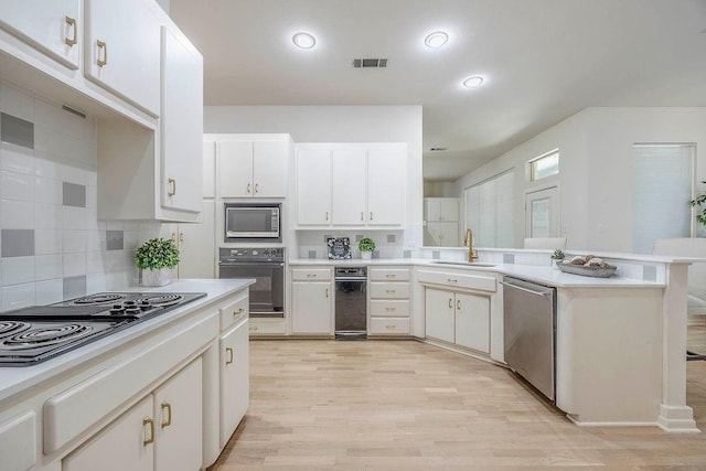 kitchen with sink, white cabinets, light hardwood / wood-style floors, tasteful backsplash, and black appliances